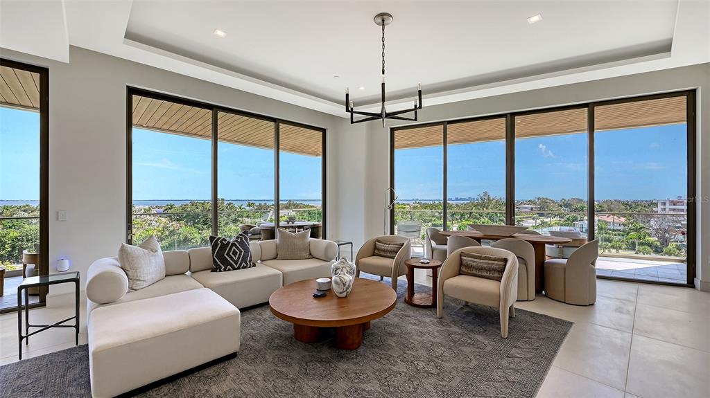 A modern living room features a large sectional, round coffee table, and floor-to-ceiling windows — 1591 GULF OF MEXICO DRIVE UNIT 512, LONGBOAT KEY, FL