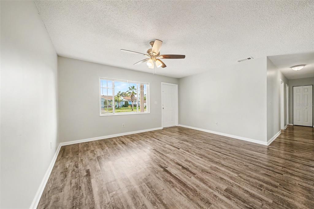 An empty living room features light gray walls, wood-look flooring, and a ceiling fan — 4814 BLARNEY DRIVE, ORLANDO, FL