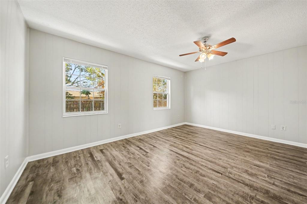 An empty bedroom features light gray paneled walls, wood-look flooring, and a ceiling fan — 4814 BLARNEY DRIVE, ORLANDO, FL
