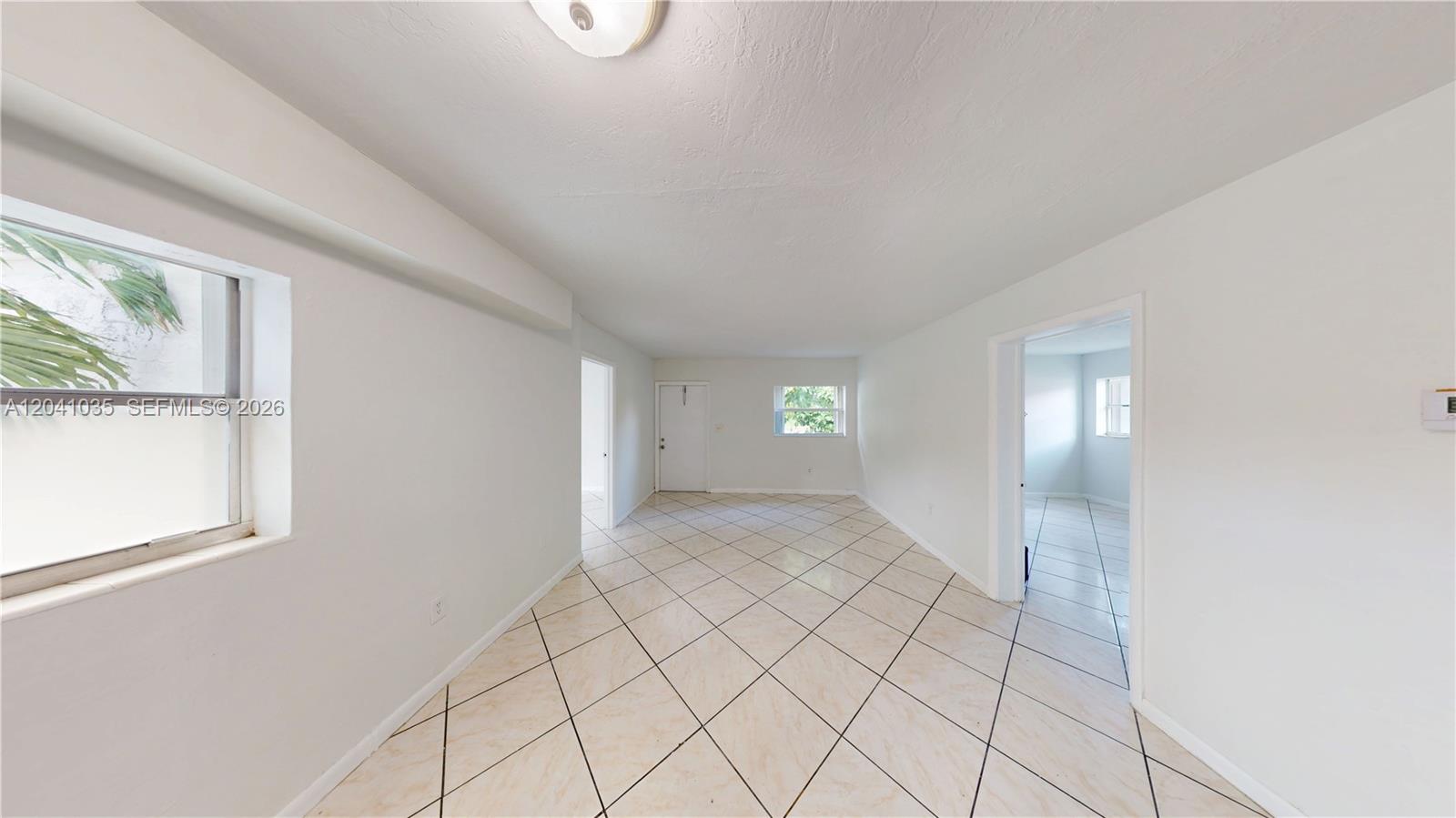 A bright, empty room features white walls, tiled floors, and doorways leading to other spaces — 6811 SW 16th St, Miami FL 33155, MIAMI, FL