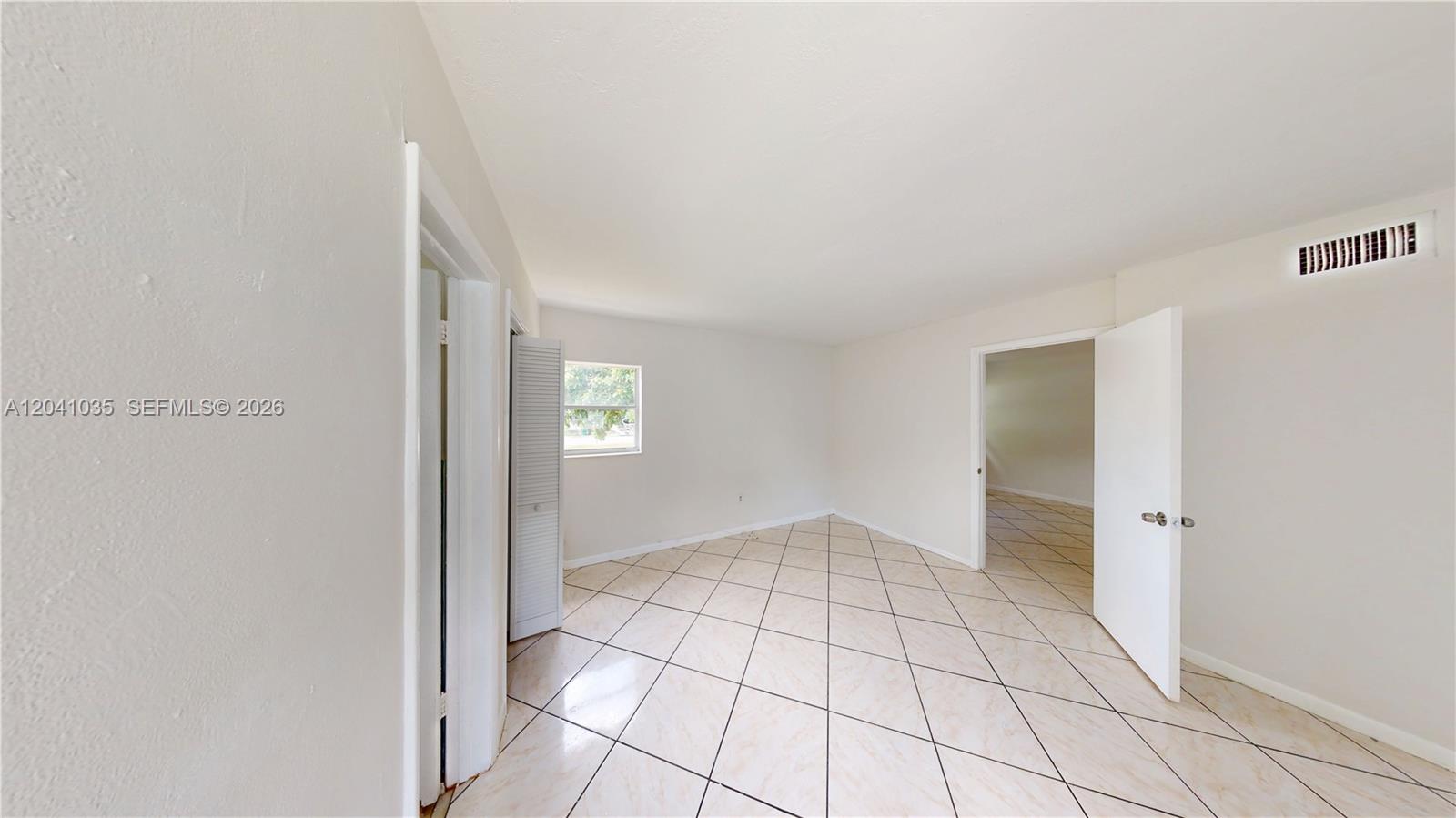 An empty room features light-colored tile flooring, white walls, and a single window — 6811 SW 16th St, Miami FL 33155, MIAMI, FL