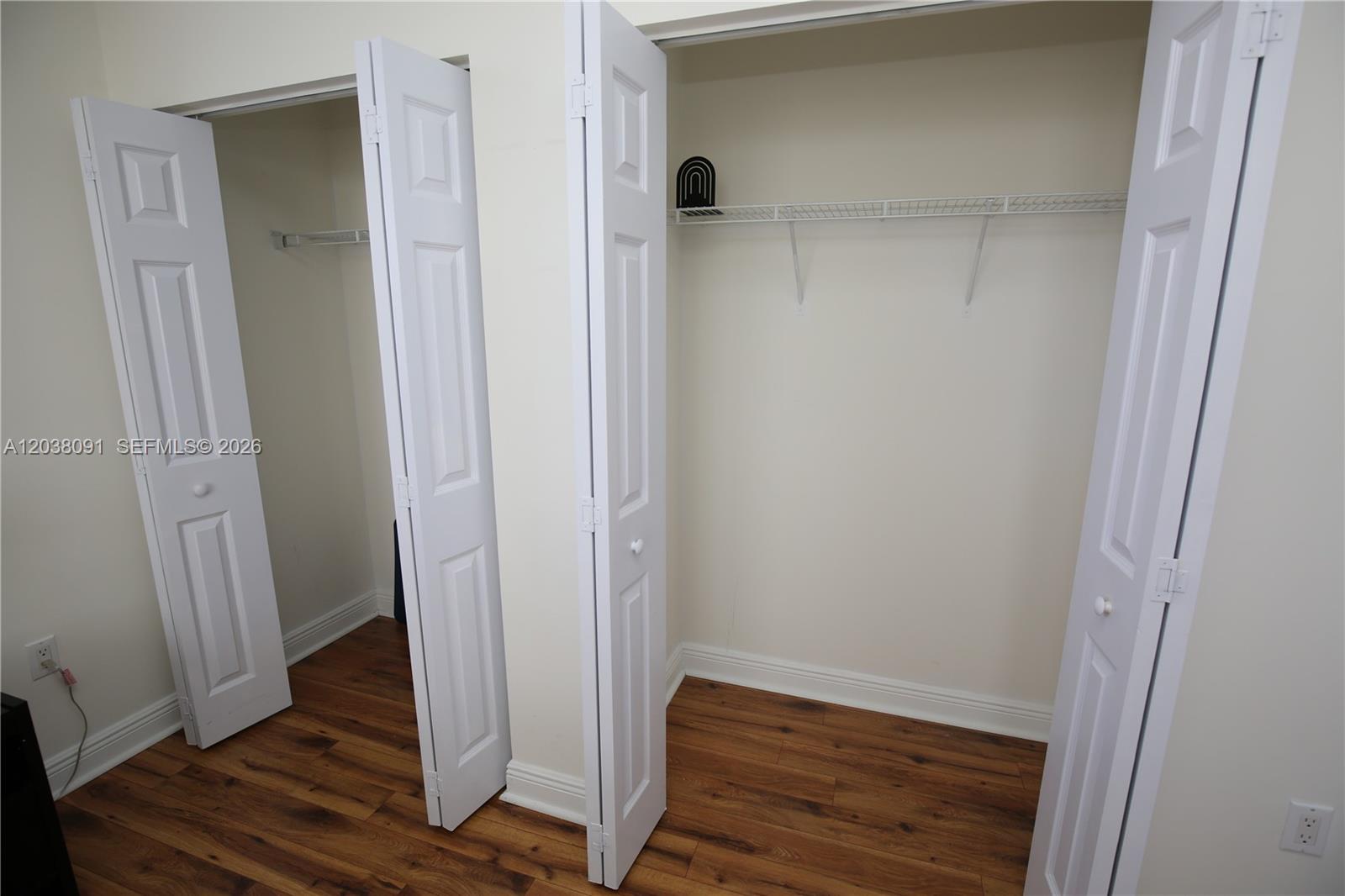 Two open closets with white bifold doors and wire shelving sit above wood-look flooring — 3232 SW 22nd Ter # 1510, Miami FL 33145, MIAMI, FL