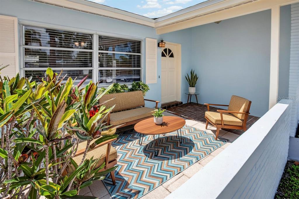 A patio with a chevron rug, mid-century modern furniture, and a light blue exterior wall — 13746 MARTINIQUE DRIVE, SEMINOLE, FL