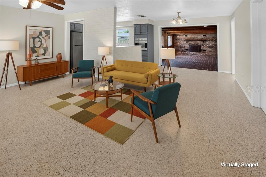 A virtually staged living room features a yellow sofa, teal chairs, and a patterned rug — 13746 MARTINIQUE DRIVE, SEMINOLE, FL