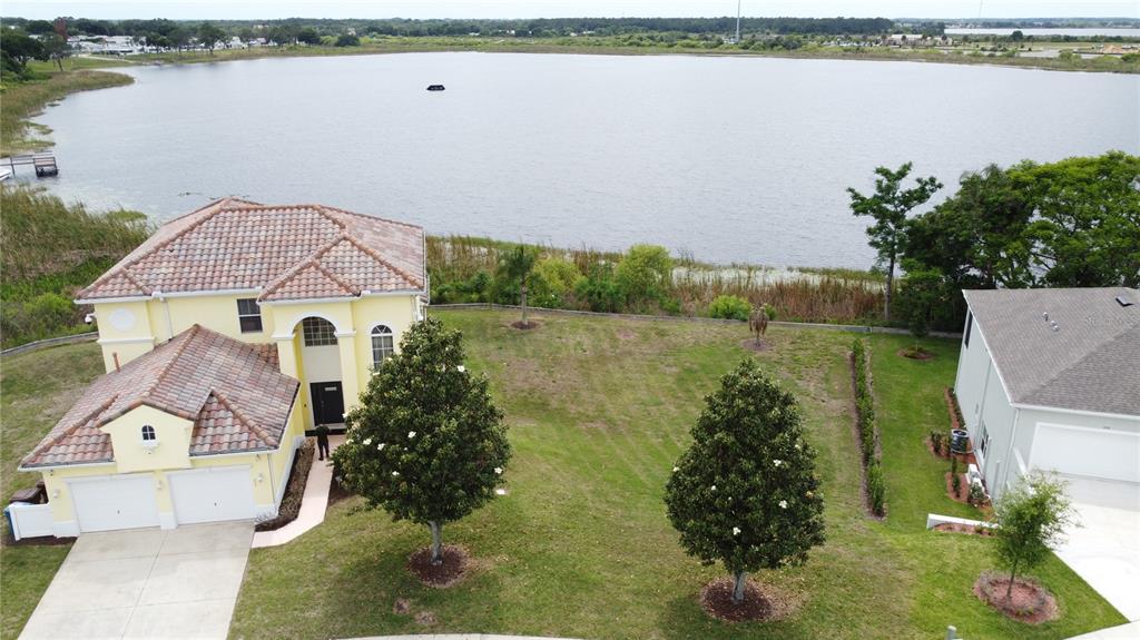 An aerial view shows a two-story yellow house with a tile roof near a lake — 354 CHEROKEE AVE, HAINES CITY, FL