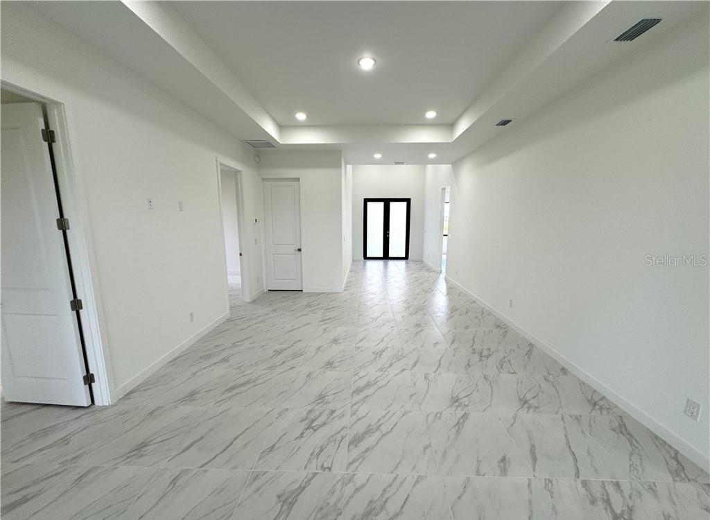 An empty room with white walls, recessed lighting, and light-colored marble-patterned tile flooring — 1247 KISMET PARKWAY W, CAPE CORAL, FL