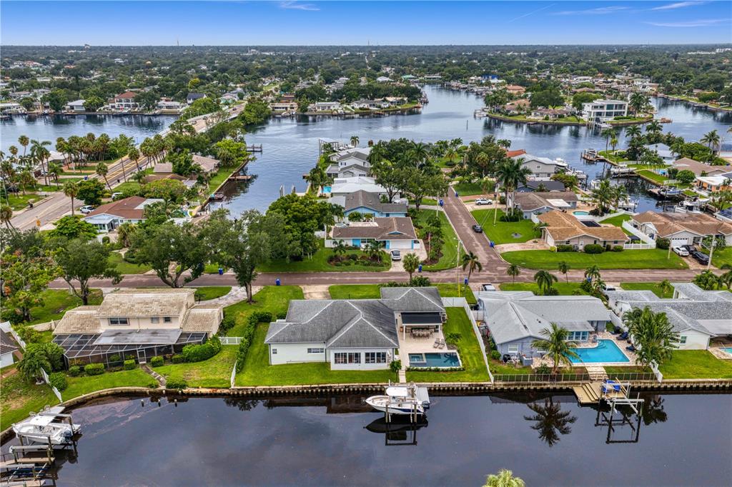An aerial view shows a waterfront house with a pool, dock, and boat in Florida — 4091 13TH WAY NE, ST PETERSBURG, FL