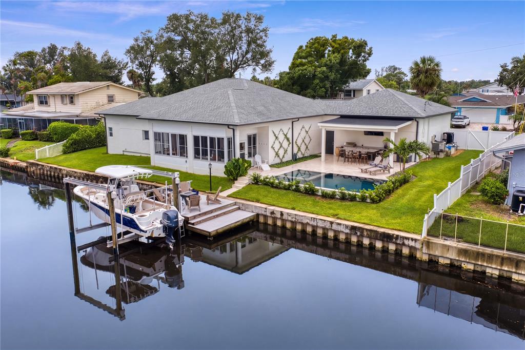 An aerial view of a waterfront house with a boat lift, pool, and covered patio — 4091 13TH WAY NE, ST PETERSBURG, FL