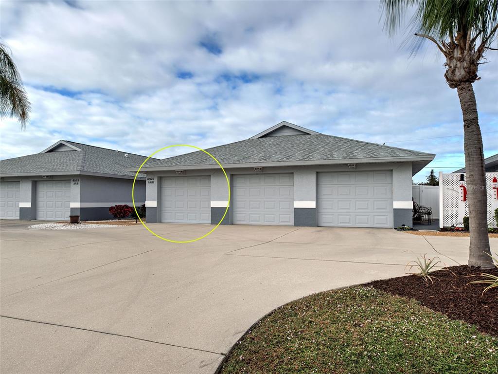 A row of gray garage doors on a residential building with a concrete driveway — 6527 HAMLET DRIVE UNIT 26B, ENGLEWOOD, FL