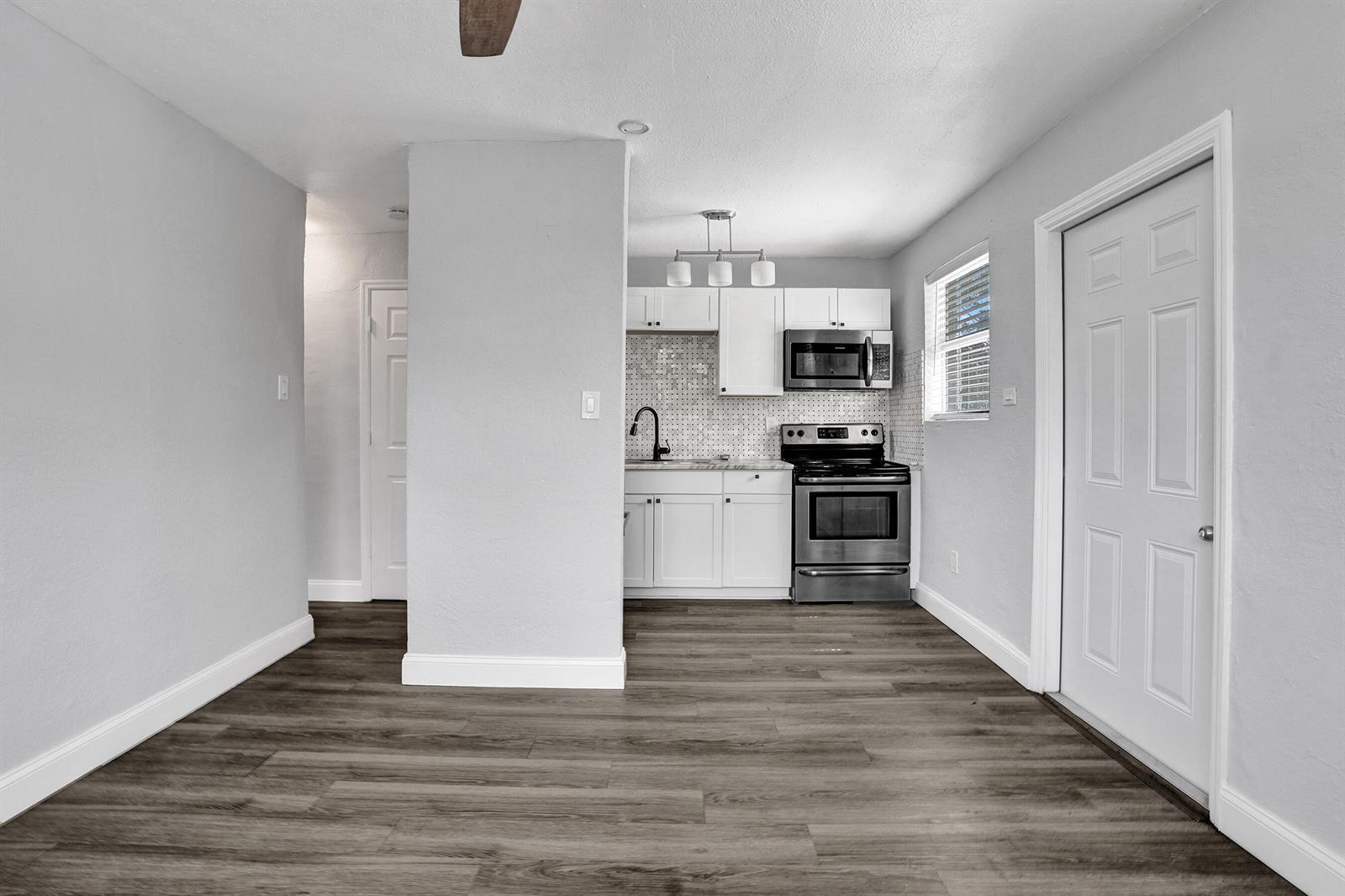 A kitchen with white cabinets, stainless steel appliances, and wood-look flooring in an open space — 2261 NW 2nd Street, Pompano Beach FL 33069, POMPANO BEACH, FL