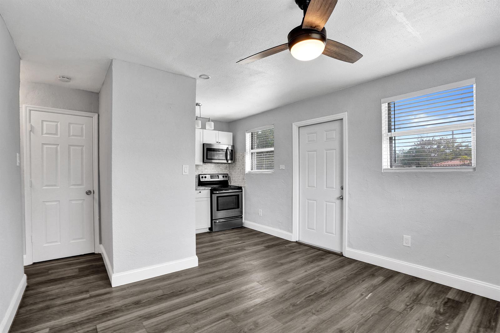 A room with gray walls, wood-look flooring, a ceiling fan, and a small kitchen area — 2261 NW 2nd Street, Pompano Beach FL 33069, POMPANO BEACH, FL
