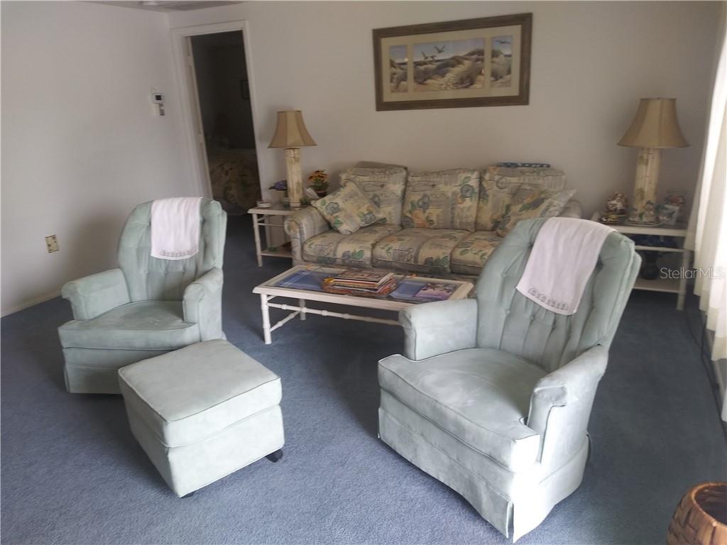 A living room features a patterned sofa, two light green armchairs, and a matching ottoman — 1261 JOPLIN AVENUE NW, PORT CHARLOTTE, FL