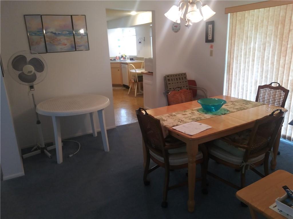 A dining room with a wooden table, chairs, and a view into the adjacent kitchen — 1261 JOPLIN AVENUE NW, PORT CHARLOTTE, FL
