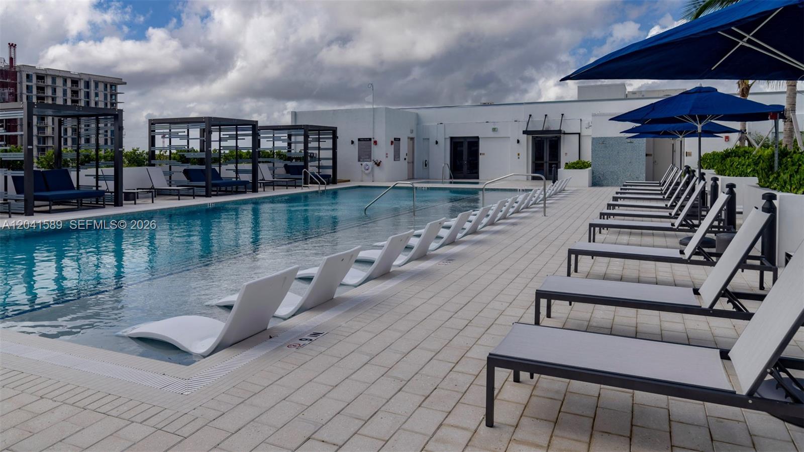 A rooftop swimming pool features lounge chairs in the water and on the paved deck — 19401 W Dixie Hwy # 421, Miami FL 33180, MIAMI, FL