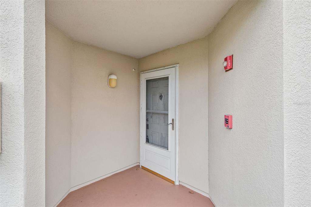 A covered entryway features a white storm door, a wall-mounted light, and fire safety equipment — 6000 BAHIA DEL MAR CIRCLE UNIT 134, ST PETERSBURG, FL