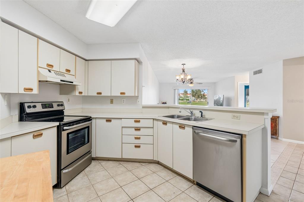 A kitchen features white cabinets, stainless steel appliances, tile flooring, and a breakfast bar — 6000 BAHIA DEL MAR CIRCLE UNIT 134, ST PETERSBURG, FL