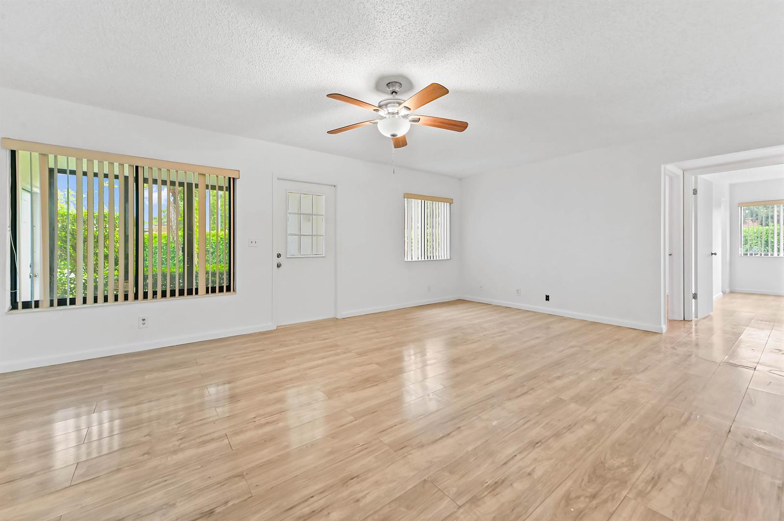 A bright living room with white walls, light wood-look flooring, and a ceiling fan — 319 Knotty Pine Circle # 1, FL 33463, FL