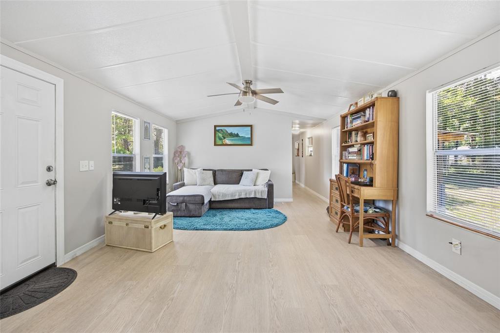 The exterior of a manufactured home features a red front door and a wooden porch — 2412 NW 116TH PLACE, GAINESVILLE, FL