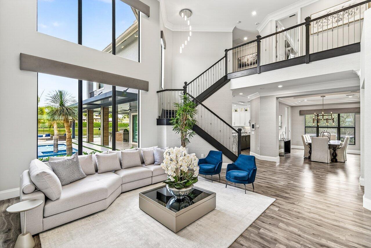 A spacious living room features a large sectional sofa, blue armchairs, and a grand staircase — 16722 Cannes Street, Delray Beach FL 33446, DELRAY BEACH, FL