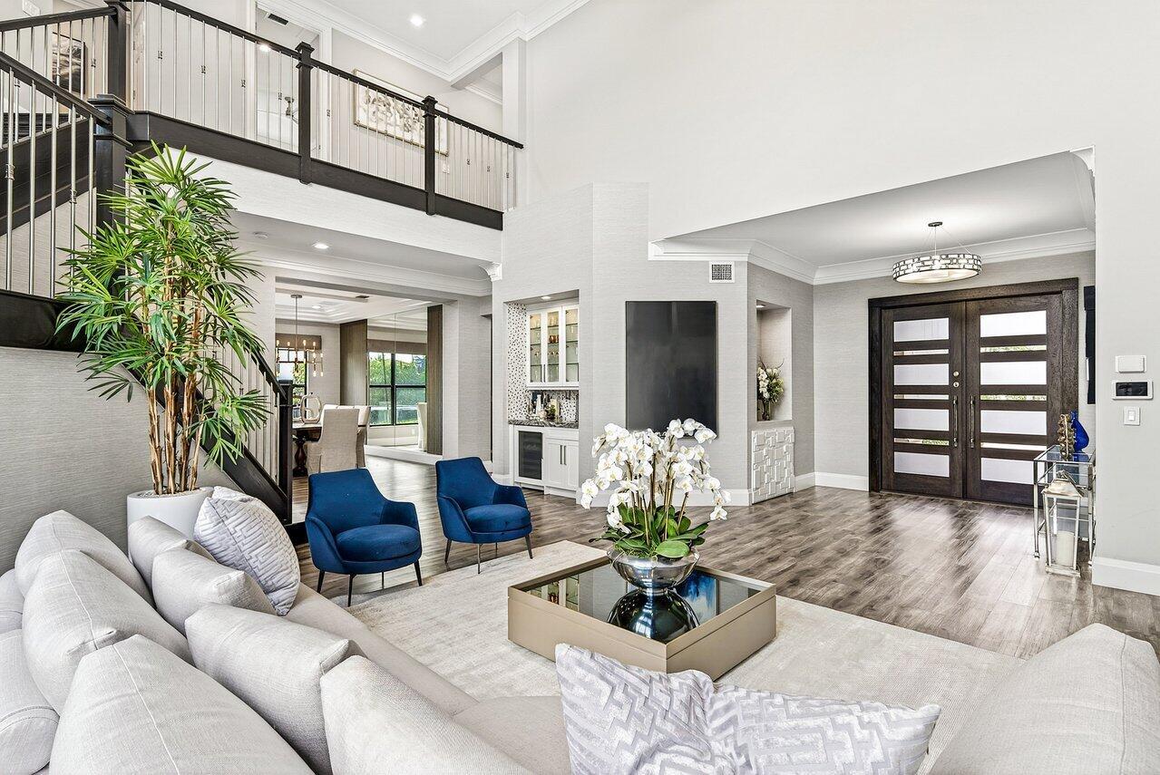 A bright, open-concept living area features a high ceiling, dark wood floors, and blue armchairs — 16722 Cannes Street, Delray Beach FL 33446, DELRAY BEACH, FL