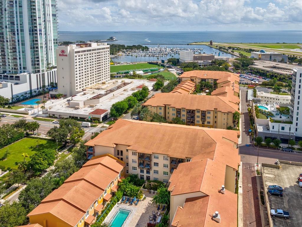 An aerial view shows a multi-story apartment complex with orange tile roofs and a pool — 200 4TH AVENUE S UNIT 225, ST PETERSBURG, FL