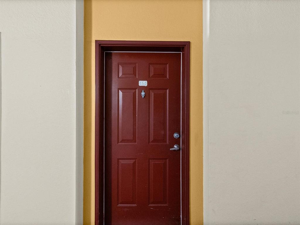 A red door with the number 225 is set within a yellow recessed wall — 200 4TH AVENUE S UNIT 225, ST PETERSBURG, FL