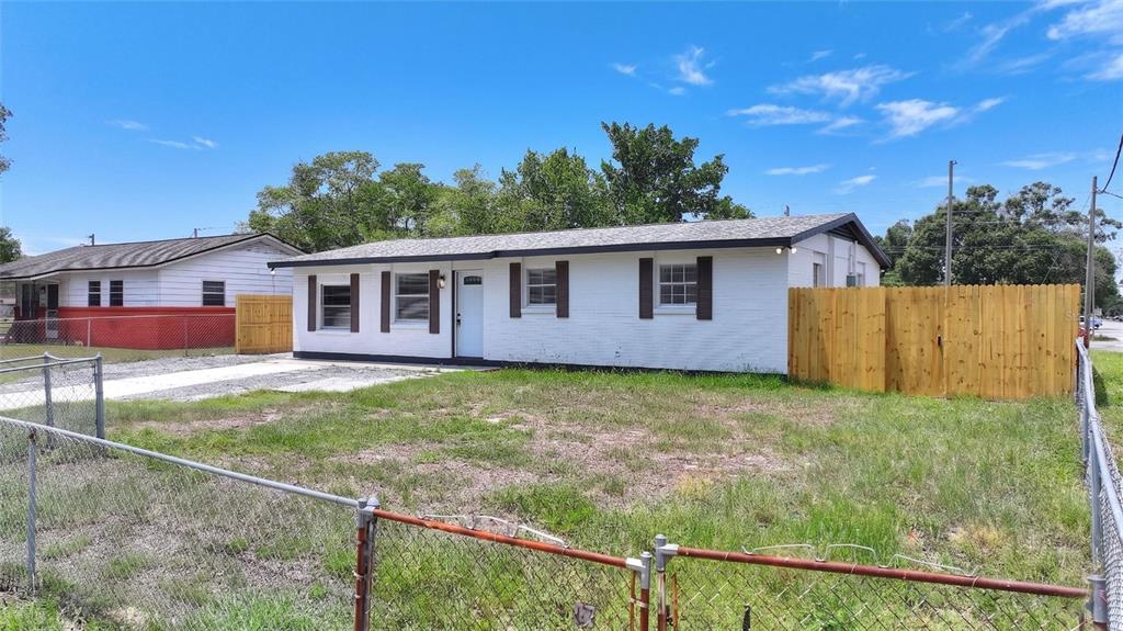 A white, single-story house with brown shutters sits on a lot with a chain-link fence — 8204 ALLAMANDA AVENUE, TAMPA, FL