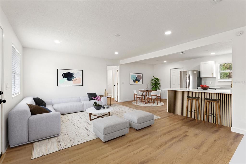 An open-concept living room and kitchen feature light wood flooring and modern neutral furniture — 8204 ALLAMANDA AVENUE, TAMPA, FL