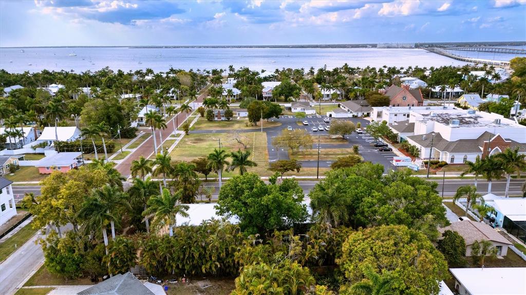 An aerial view shows a coastal neighborhood with palm trees, a parking lot, and water — 521 W OLYMPIA AVENUE, PUNTA GORDA, FL