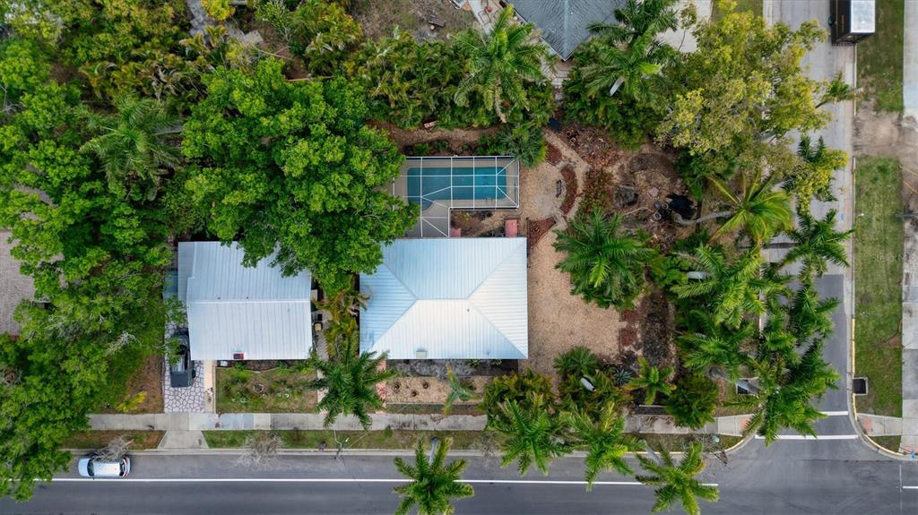 An aerial view shows a house with a metal roof, a pool, and lush landscaping — 521 W OLYMPIA AVENUE, PUNTA GORDA, FL