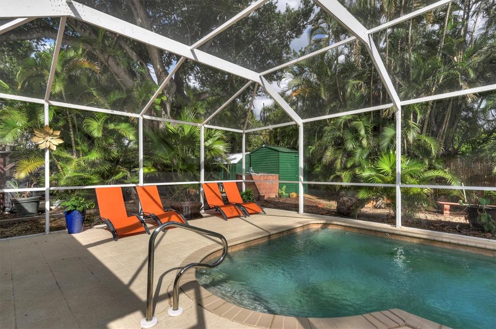 A screened-in swimming pool area features four orange lounge chairs on a concrete deck — 521 W OLYMPIA AVENUE, PUNTA GORDA, FL