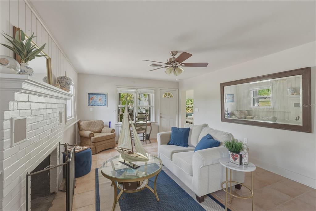 A living room features a white brick fireplace, a sofa, a coffee table, and a mirror — 521 W OLYMPIA AVENUE, PUNTA GORDA, FL