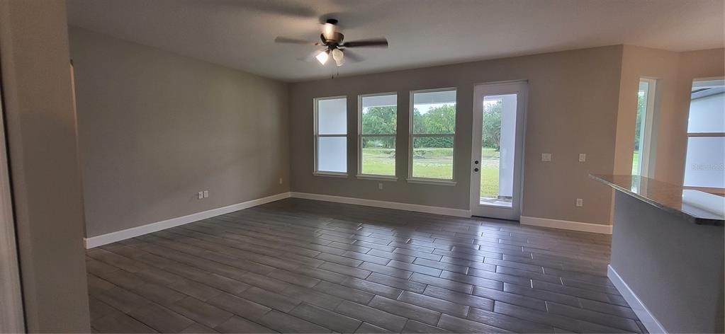 A living room with gray tile flooring, a ceiling fan, and a glass door to outside — 1685 E OSCEOLA ROAD, GENEVA, FL