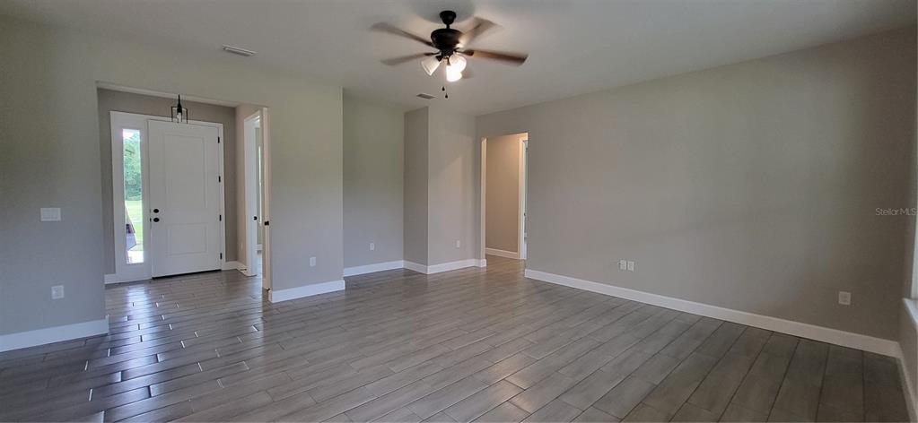 An empty room with gray wood-look tile flooring, a ceiling fan, and a white front door — 1685 E OSCEOLA ROAD, GENEVA, FL