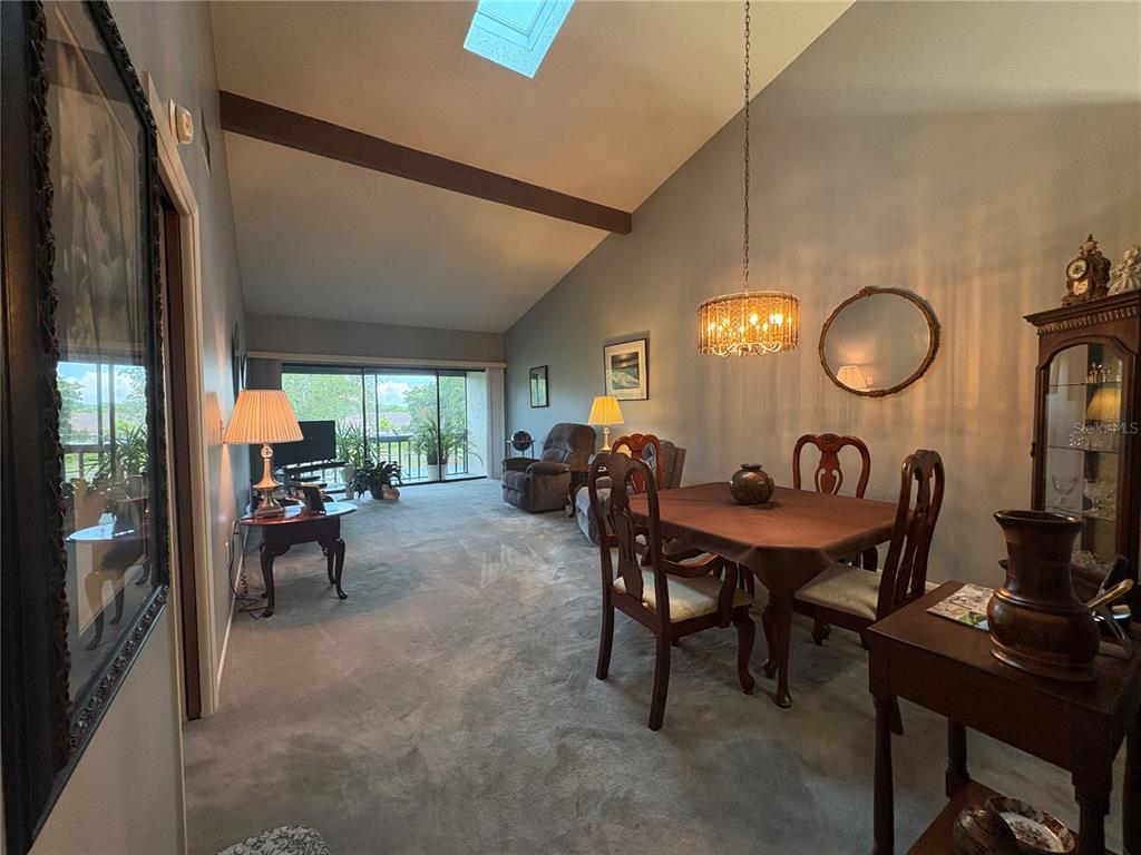 A dining and living area features a vaulted ceiling, skylight, carpeted floors, and a balcony — 7214 CLOISTER DRIVE UNIT 7214, SARASOTA, FL