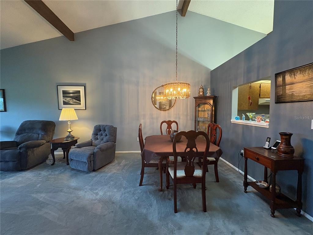 A dining area with a vaulted ceiling, carpeted floors, and a dark wood table set — 7214 CLOISTER DRIVE UNIT 7214, SARASOTA, FL