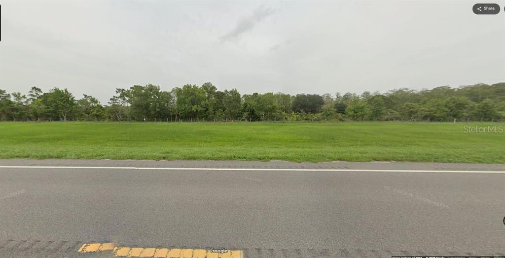 A flat, grassy vacant lot sits alongside a paved road with trees in the background — S KENANSVILLE ROAD, OKEECHOBEE, FL