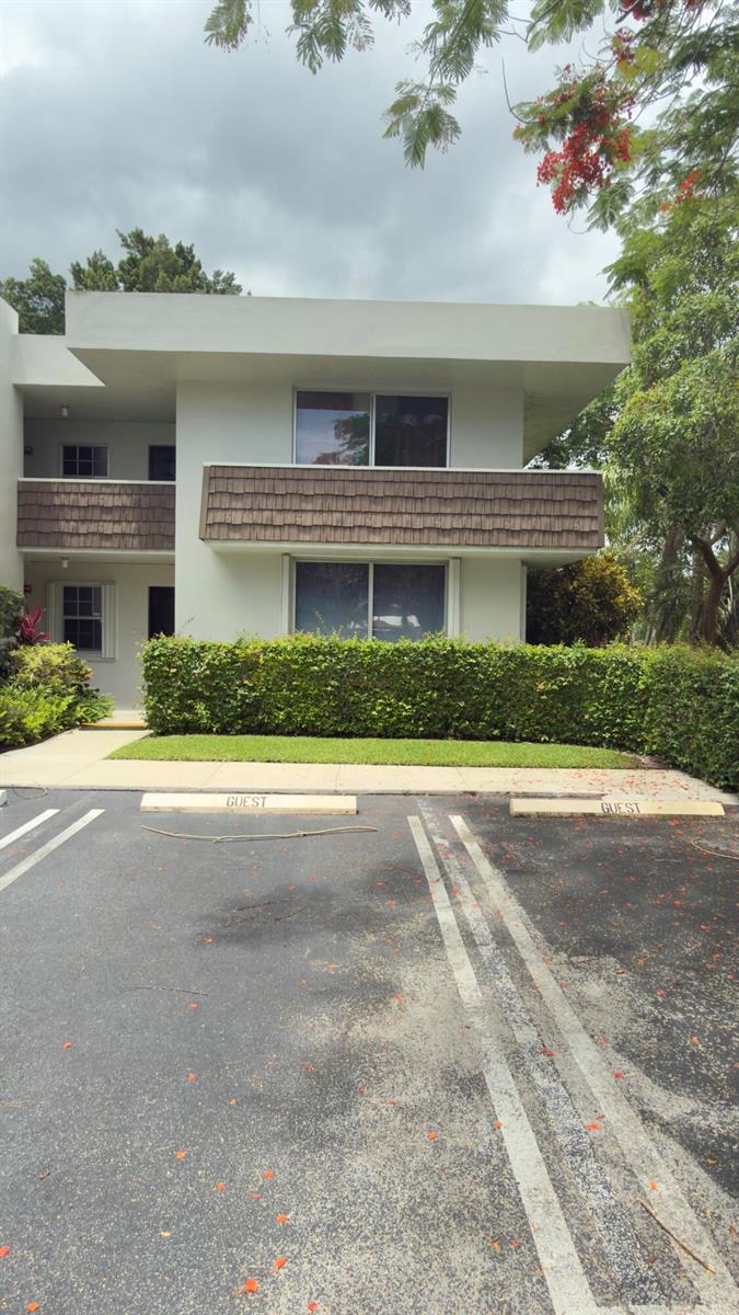 A two-story apartment building exterior features a balcony, guest parking spaces, and a manicured hedge — 4031 N Cypress Drive # 101, Pompano Beach FL 33069, POMPANO BEACH, FL