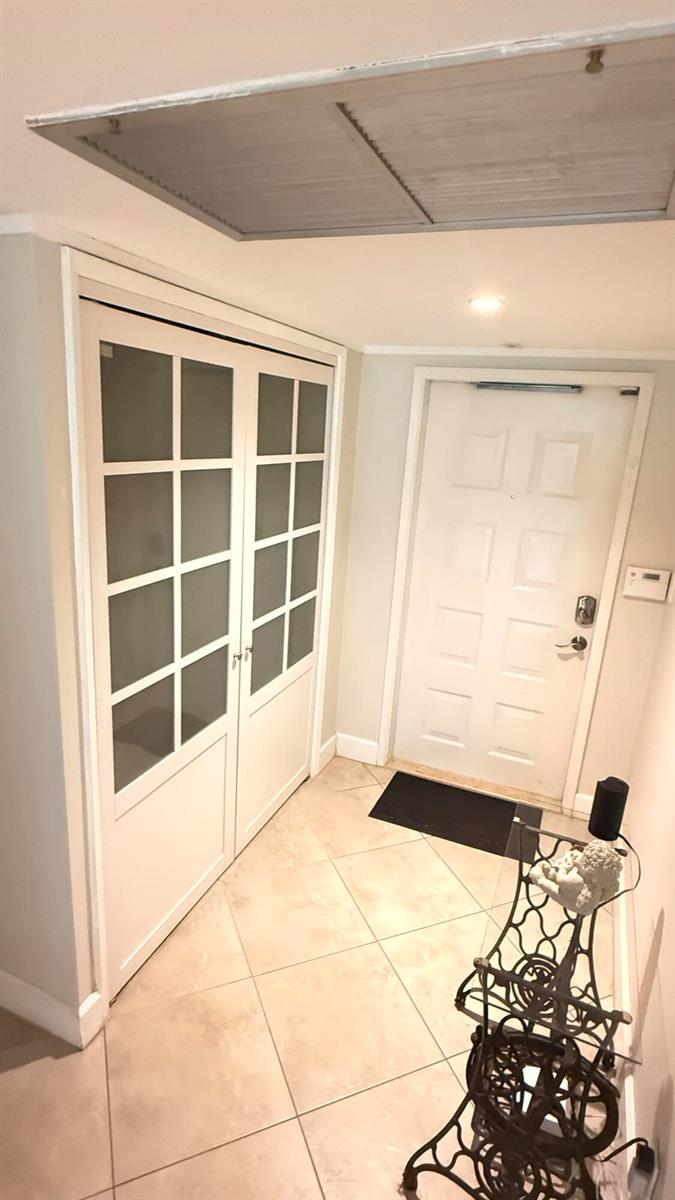 An entryway features light-colored tile flooring, a white front door, and a glass-paneled closet door — 4031 N Cypress Drive # 101, Pompano Beach FL 33069, POMPANO BEACH, FL