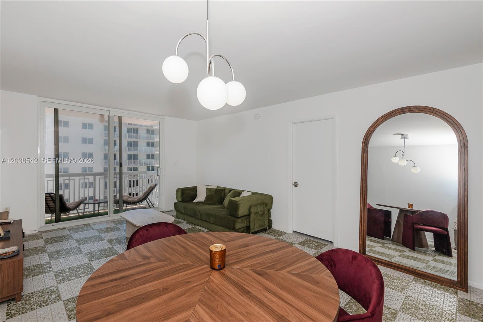 A dining area with a round wooden table and velvet chairs sits before a large mirror — 401 Ocean Dr # 810, Miami Beach FL 33139, MIAMI BEACH, FL
