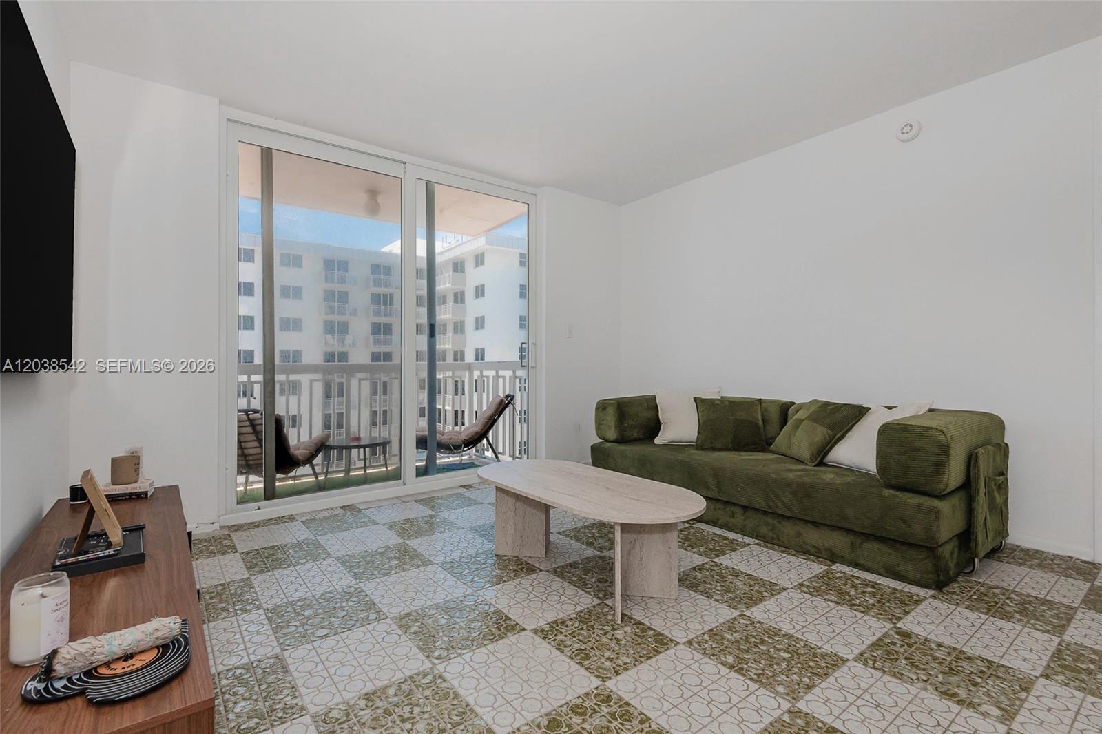 A living room features a green sofa, a stone coffee table, and patterned tile flooring — 401 Ocean Dr # 810, Miami Beach FL 33139, MIAMI BEACH, FL