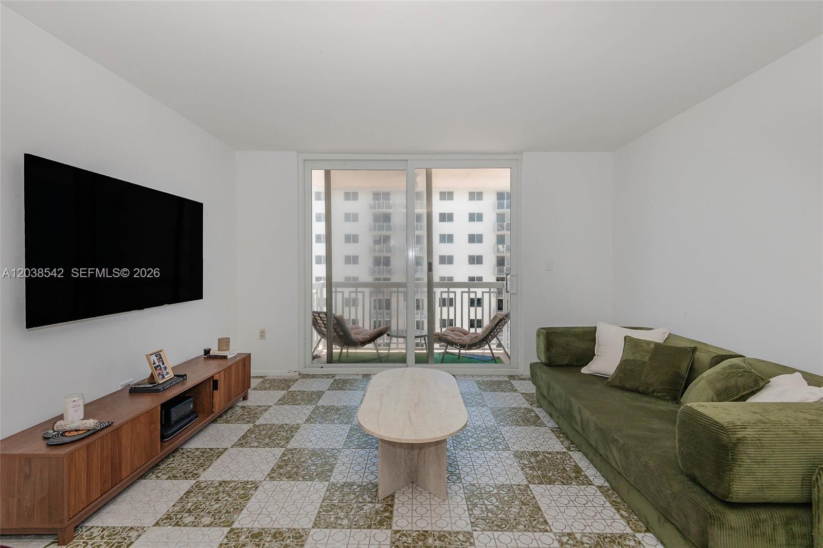 A living room features a green sofa, a television, and patterned tile flooring — 401 Ocean Dr # 810, Miami Beach FL 33139, MIAMI BEACH, FL