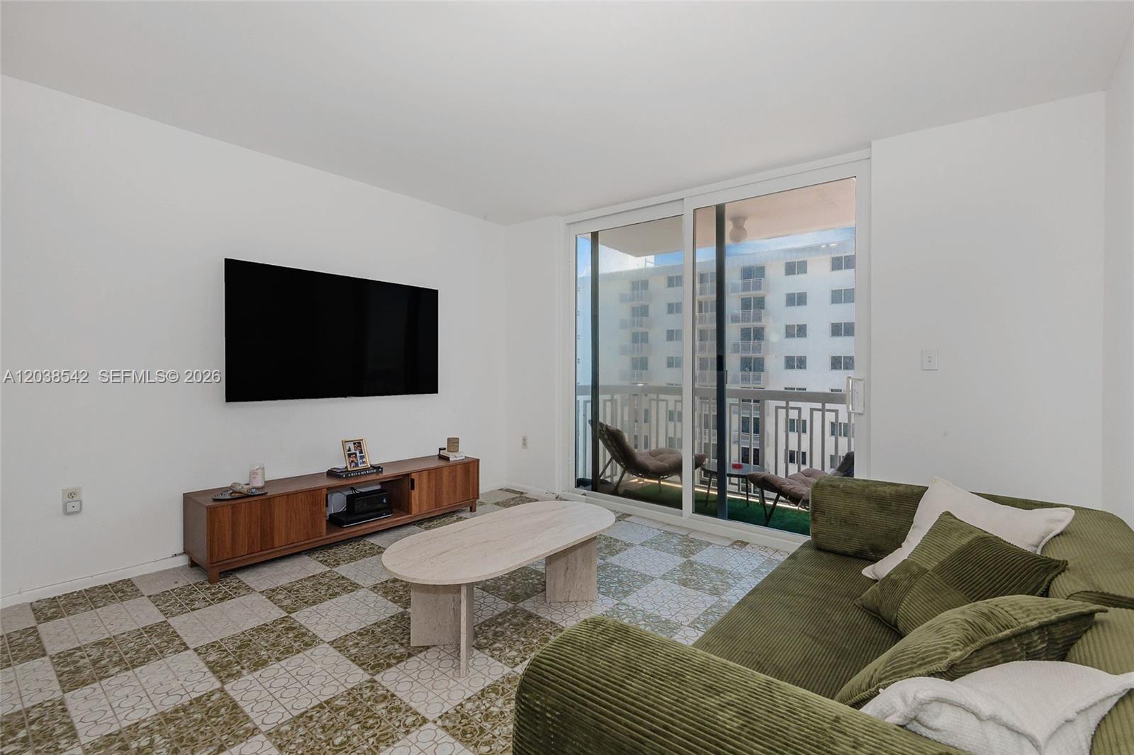 A living room features a green corduroy sofa, a TV, and patterned tile flooring — 401 Ocean Dr # 810, Miami Beach FL 33139, MIAMI BEACH, FL