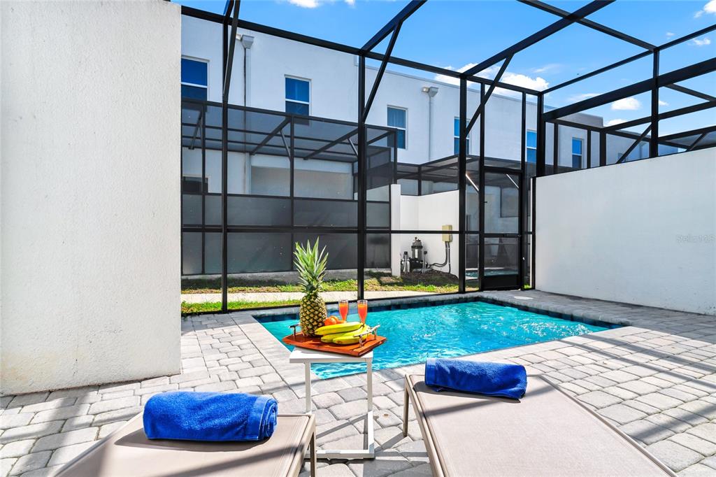 A screened-in patio features a small swimming pool, two lounge chairs, and a fruit tray — 637 TRIKOMO DRIVE DRIVE, DAVENPORT, FL