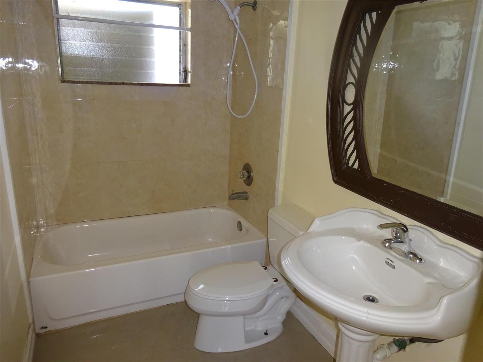 A bathroom features a white pedestal sink, a toilet, and a bathtub with tiled walls — 740 E Evanston Circle E, Fort Lauderdale FL 33312, FORT LAUDERDALE, FL
