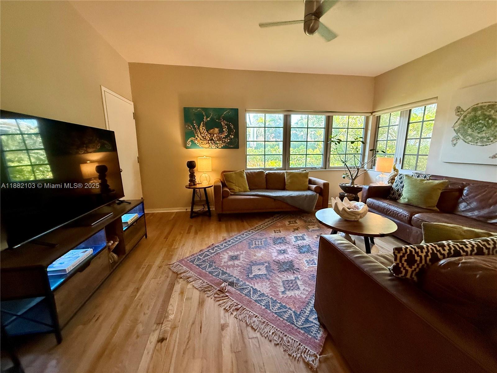 A living room features hardwood floors, a patterned area rug, and two leather sofas — 1600 Michigan Ave # 1, Miami Beach FL 33139, MIAMI BEACH, FL