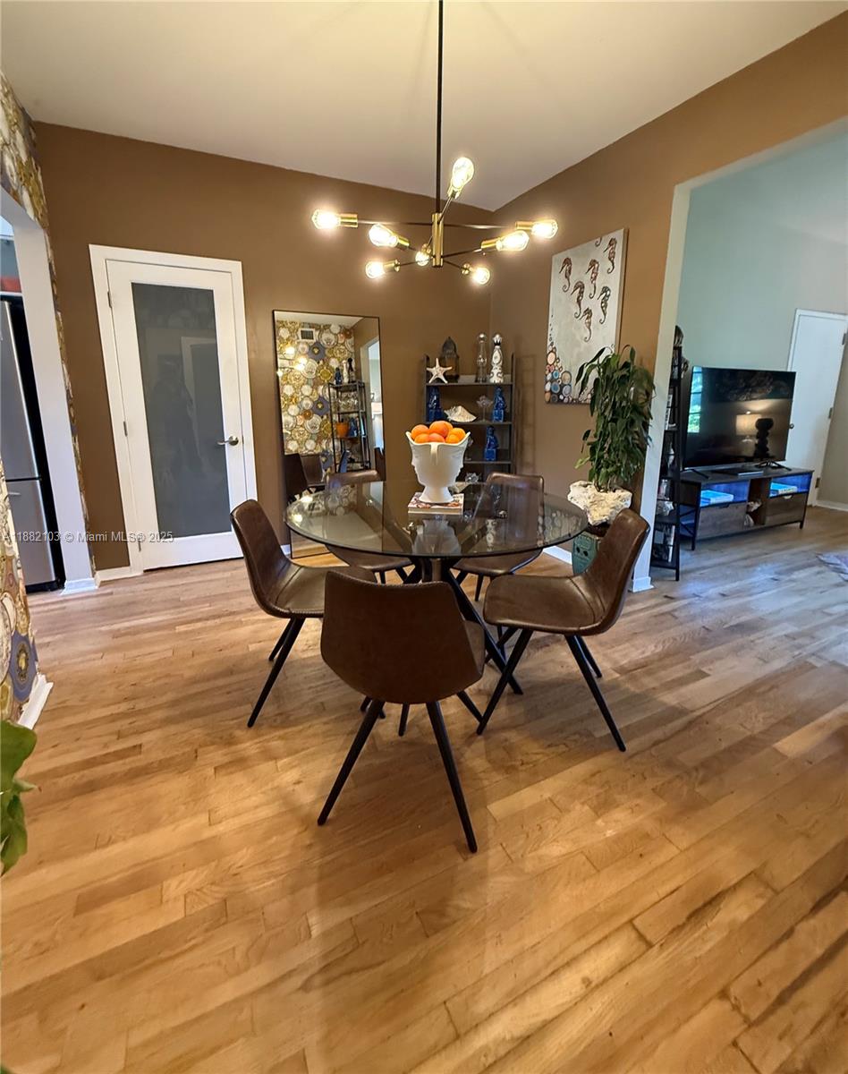 A dining room features a glass-topped table, four brown chairs, and a modern chandelier — 1600 Michigan Ave # 1, Miami Beach FL 33139, MIAMI BEACH, FL