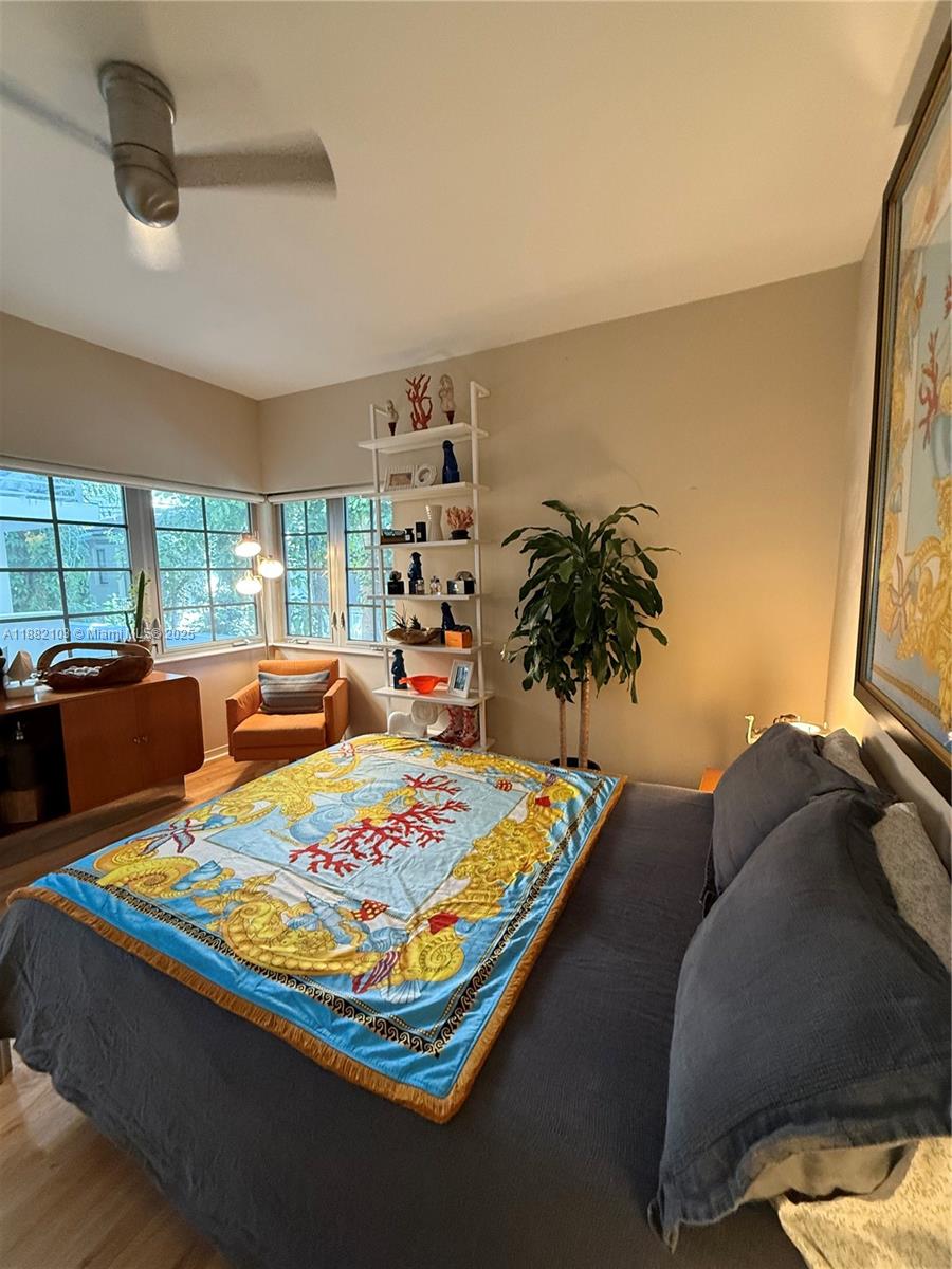 A bedroom features a bed with a patterned throw, a white shelving unit, and windows — 1600 Michigan Ave # 1, Miami Beach FL 33139, MIAMI BEACH, FL
