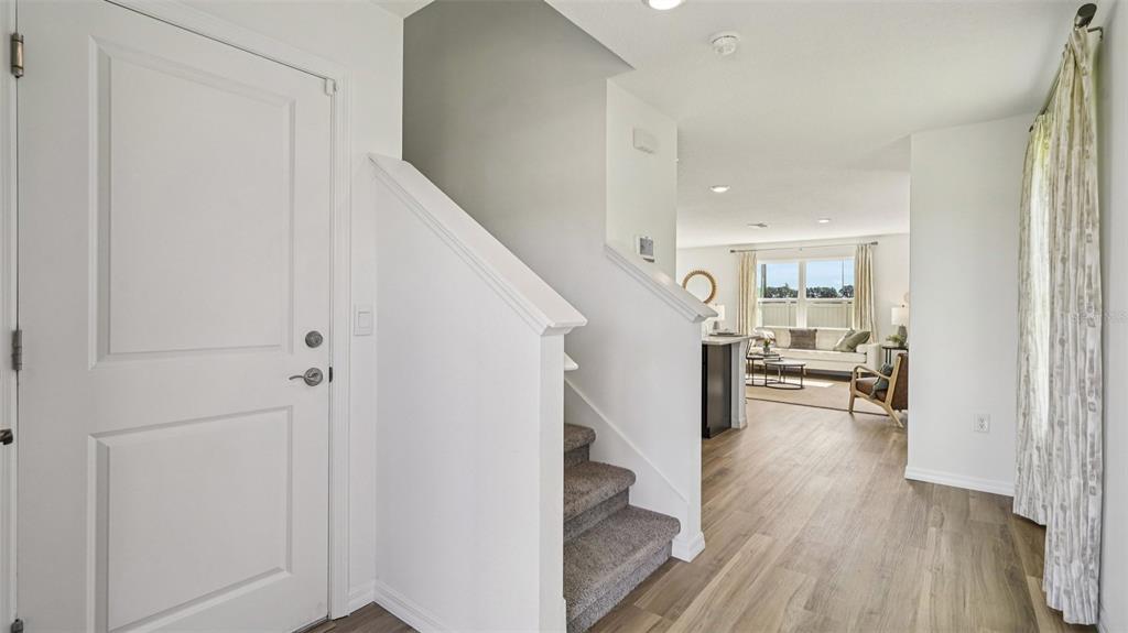An entryway features a white door, carpeted stairs, and a view into an open living area — 9091 SW 47TH COURT, OCALA, FL