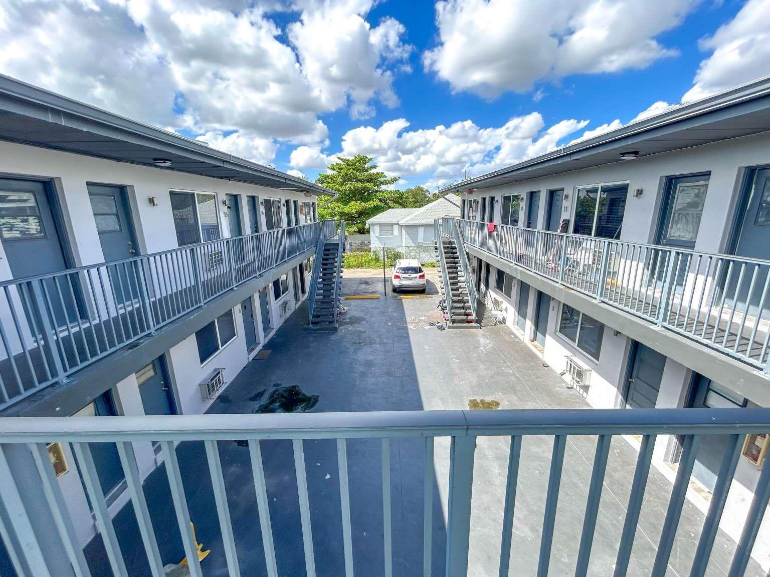 An exterior view of a two-story apartment complex with a central courtyard and metal staircases — 734 NW 80th Street, Miami FL 33150, MIAMI, FL